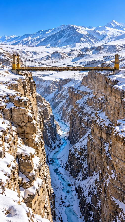 Suspension bridge over a snowy gorge in Spiti